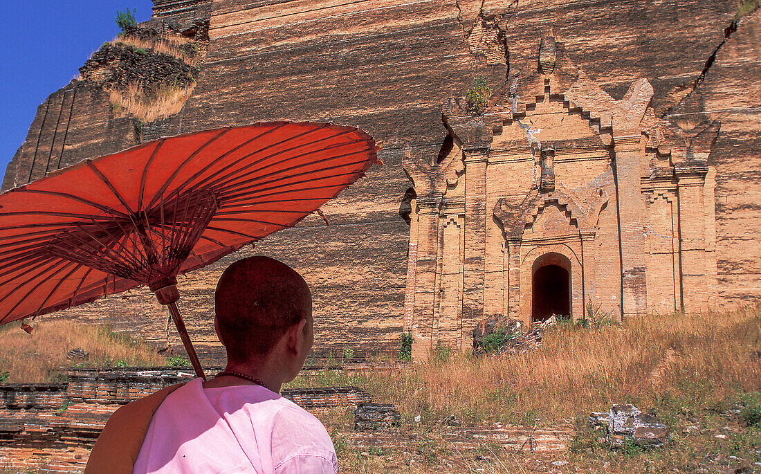 Myanmar, Mingun, Mandalay Division, Buddhist nun in front of old Buddhist temple ruined by earthquake