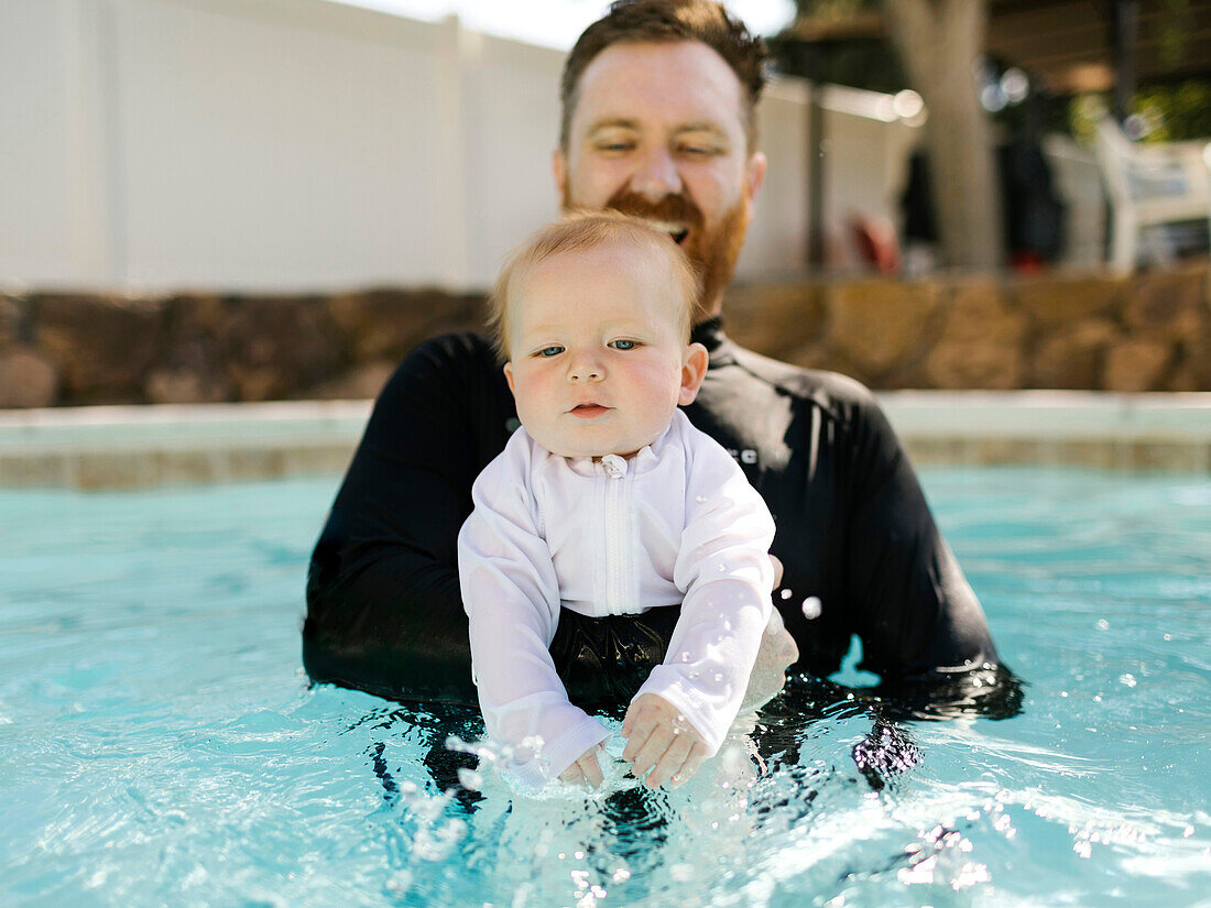 Father with baby son (12-17 months) in swimming pool