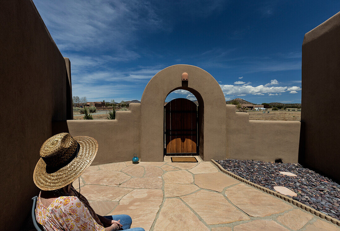 USA, New Mexico, Santa Fe, Ältere Frau mit Strohhut sitzt auf der Veranda in der Nähe des Hauses