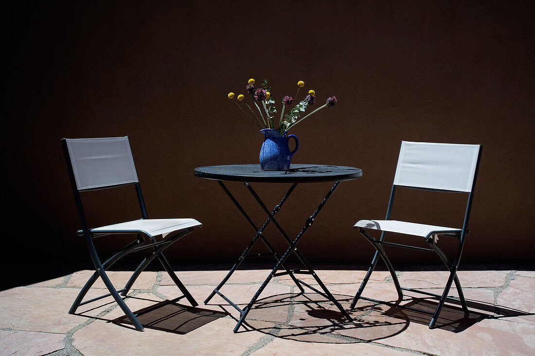 Stühle und Tisch mit Blumenstrauß auf der Veranda