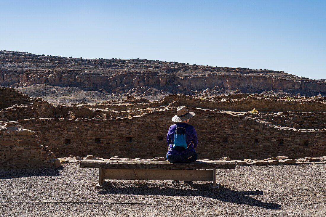 USA, New Mexico, Chaco Canyon National Historic Park, Rückansicht einer Frau, die in der archäologischen Stätte Pueblo Bonito sitzt
