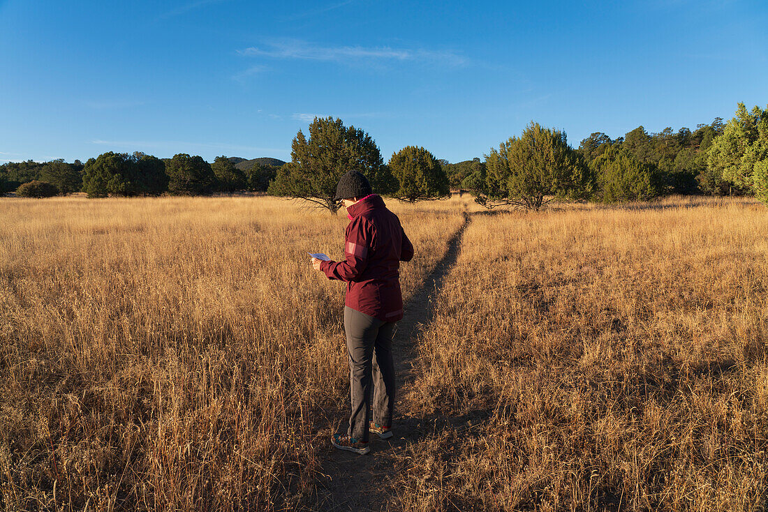 USA, New Mexico, Silver City, Frau auf Fußweg über grasbewachsenes Feld mit Blick auf eine Landkarte