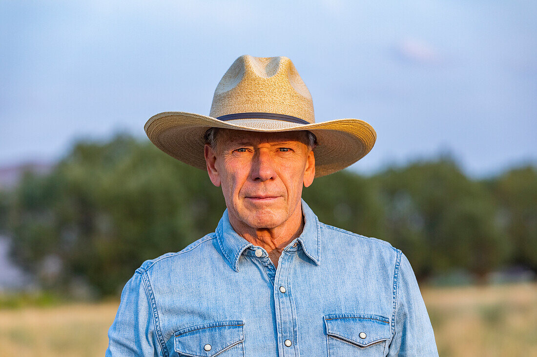 Porträt eines älteren Mannes in Jeanshemd und Cowboyhut