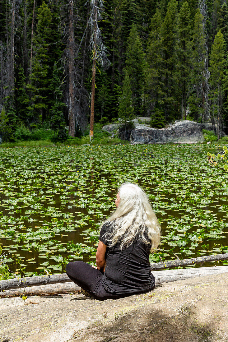 USA, Idaho, Stanley, Woman enjoying tranquility at lily pond near Sun Valley