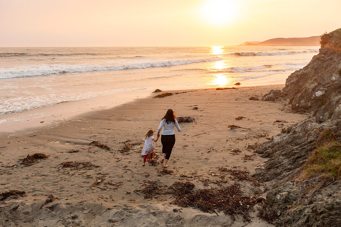 USA, Kalifornien, Cayucos, Mutter und Tochter (4-5) am Strand bei Sonnenuntergang