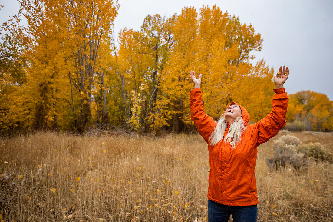 USA, Idaho, Bellevue, Smiling woman with arms raised in grassy meadow in Autumn