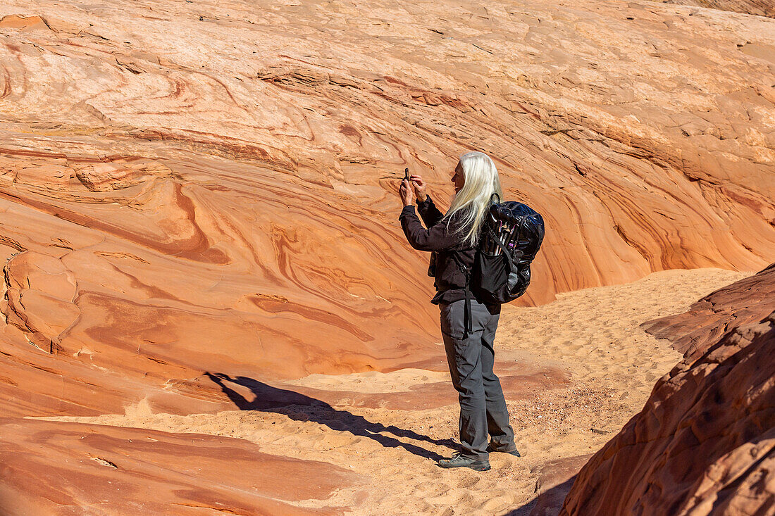 Vereinigte Staaten, Utah, Escalante, Älterer Wanderer beim Fotografieren von Felsformationen