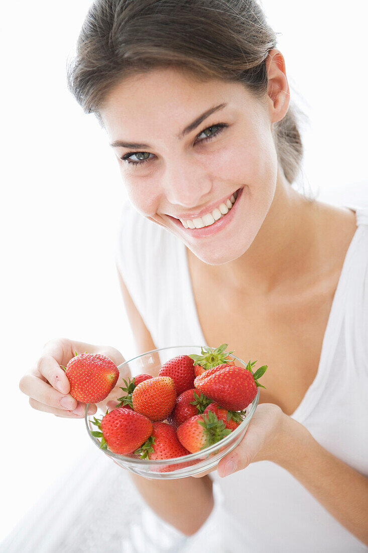 Smiling woman eating strawberries