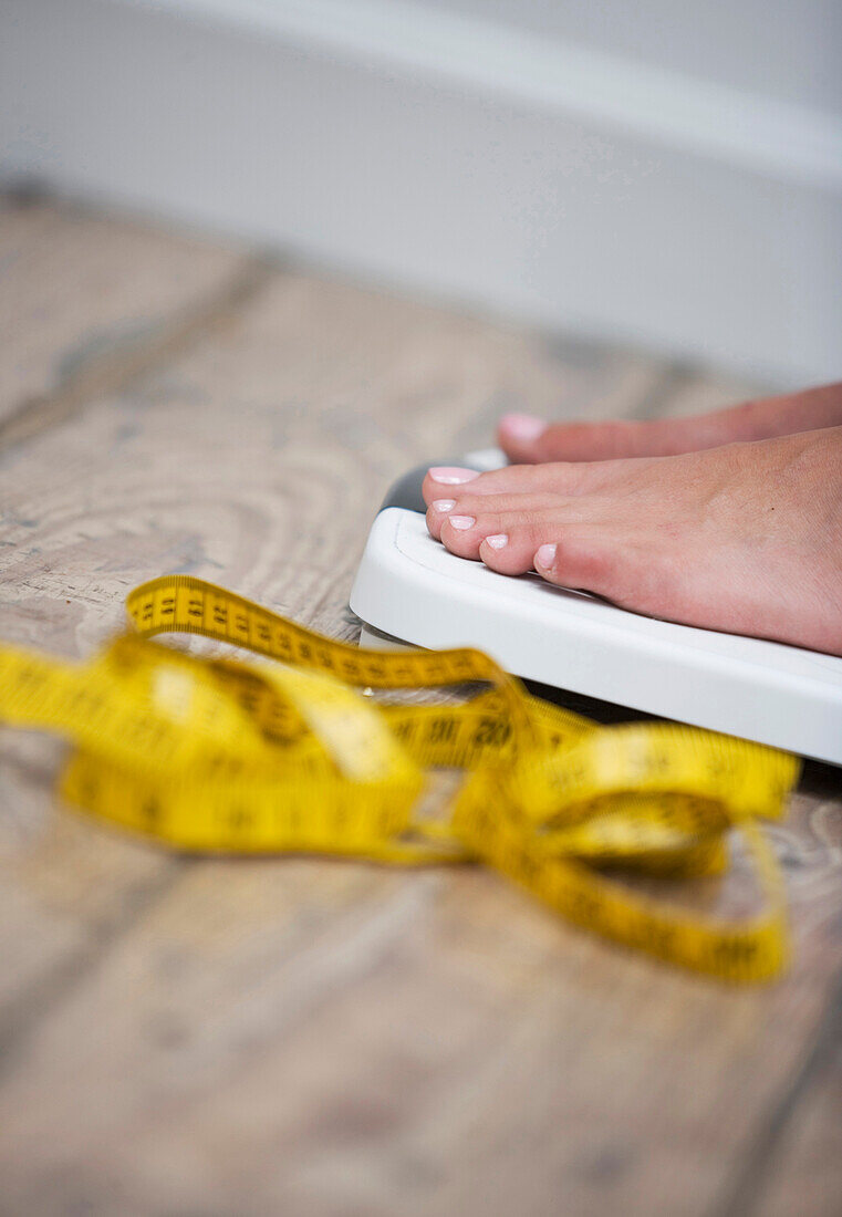 Tape measure next to woman standing on scale