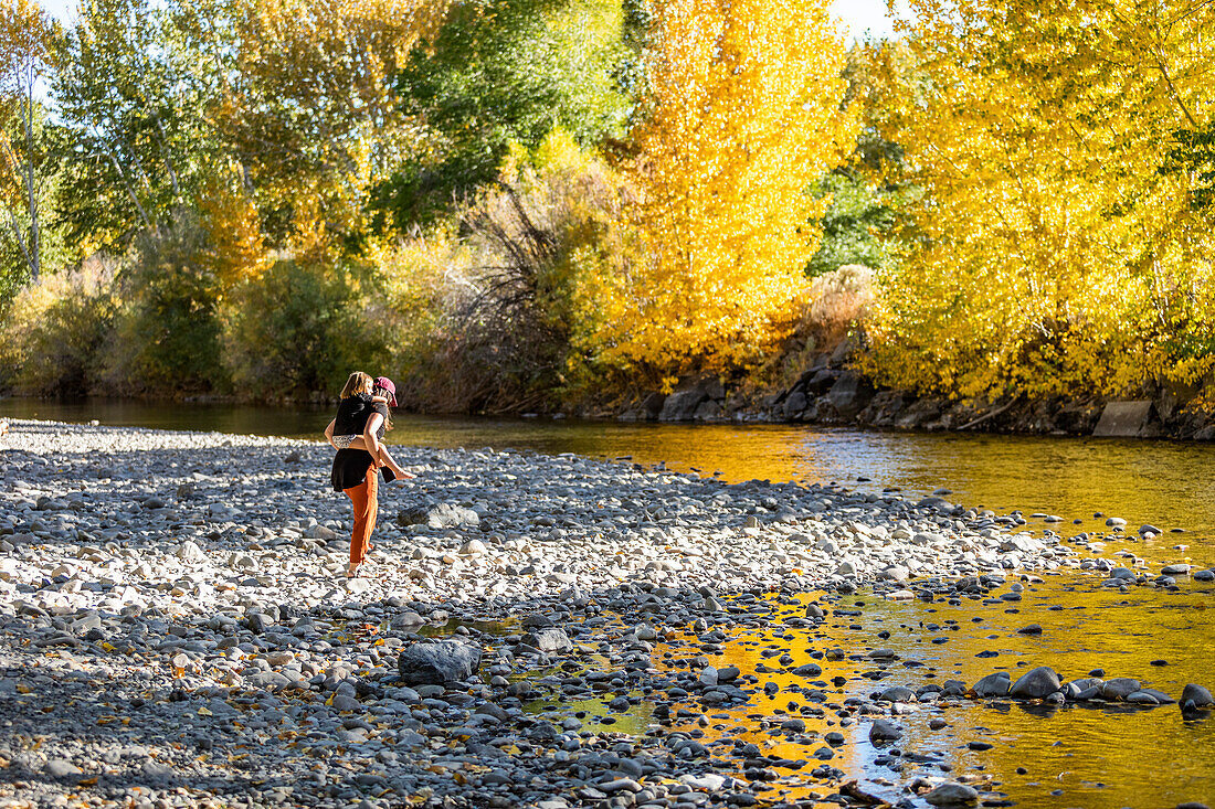 USA, Idaho, Bellevue, Mother giving daughter (6-7) piggyback ride at Big Wood River