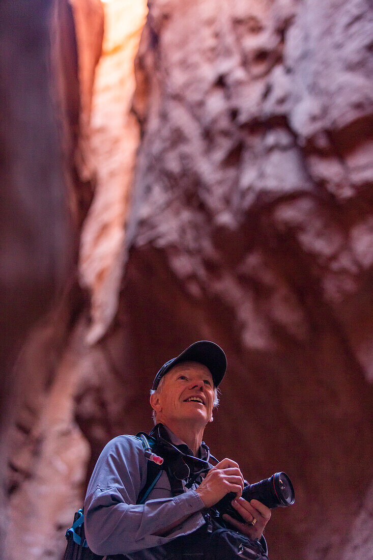 Vereinigte Staaten, Utah, Escalante, Älterer männlicher Wanderer mit Kamera im Canyon