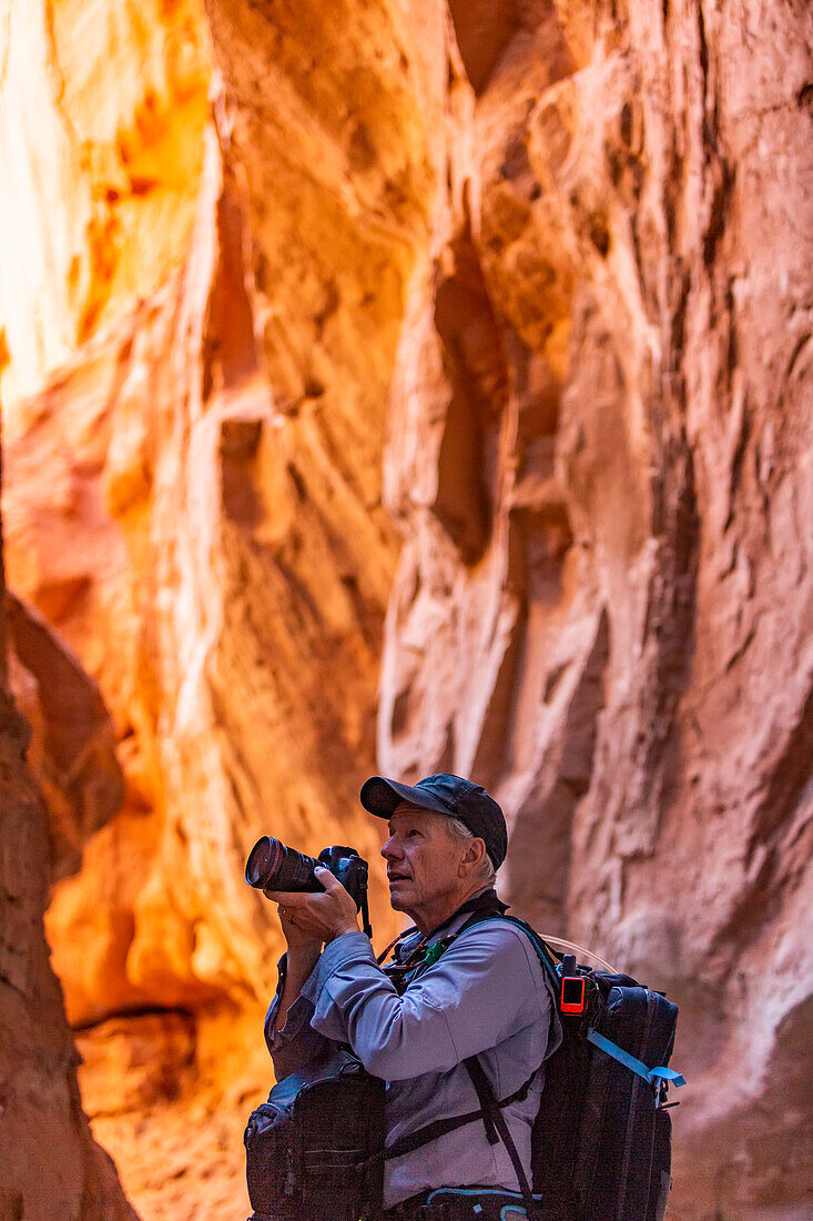 United States, Utah, Escalante, Senior hiker exploring and photographing rock formations in Kodachrome Basin State Park near Escalante Grand Staircase National Monument