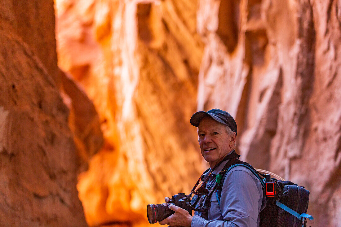 Vereinigte Staaten, Utah, Escalante, Älterer Wanderer beim Erkunden und Fotografieren von Felsformationen im Kodachrome Basin State Park in der Nähe des Escalante Grand Staircase National Monument