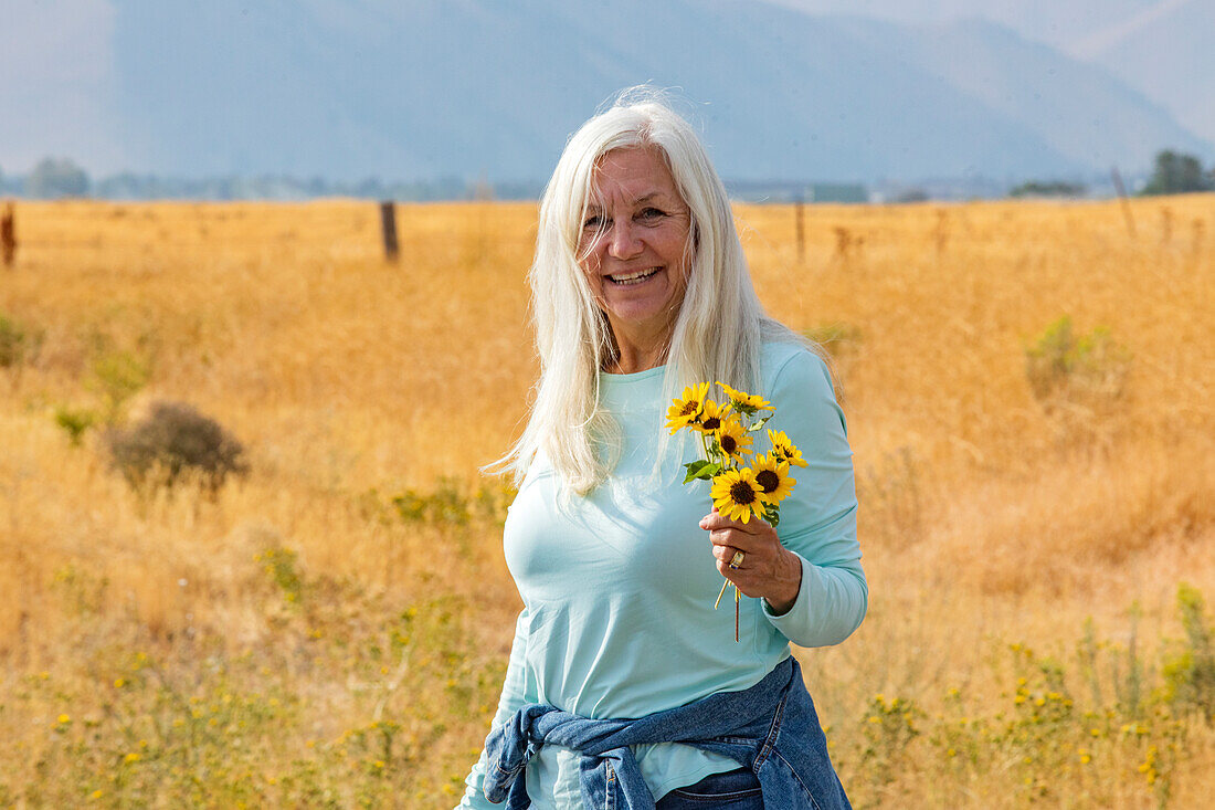 USA, Idaho, Bellevue, Porträt einer älteren Frau mit einem Strauß Sonnenblumen