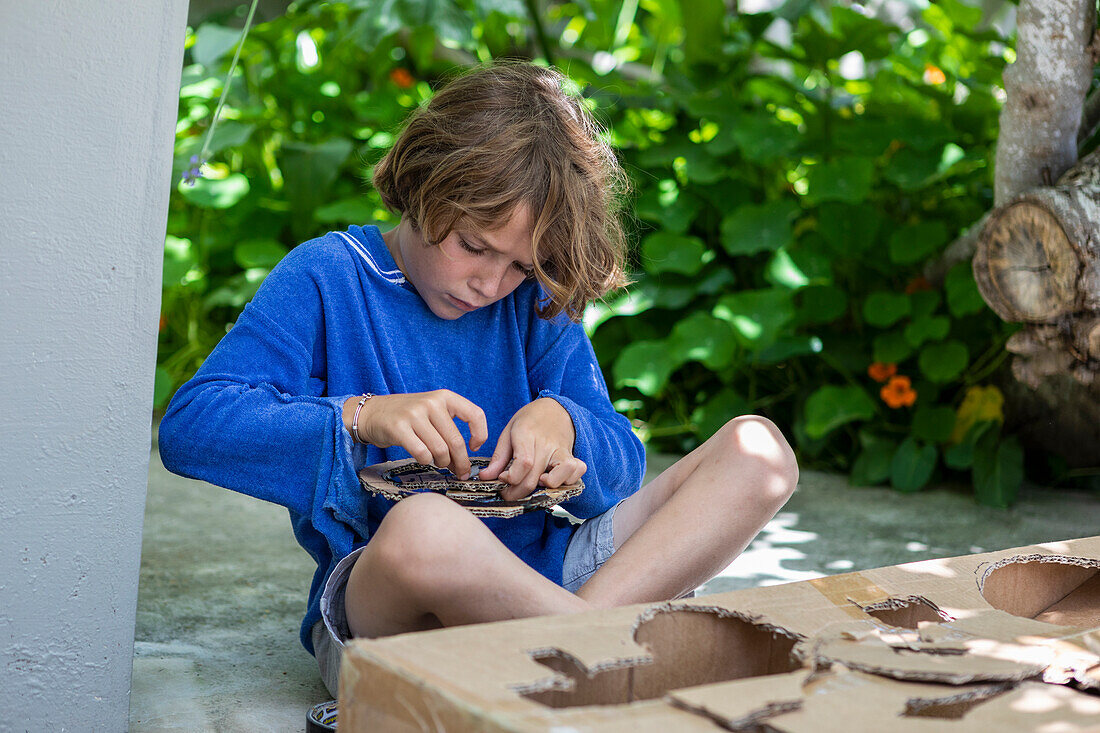 Boy (8-9) cutting a cardboard box