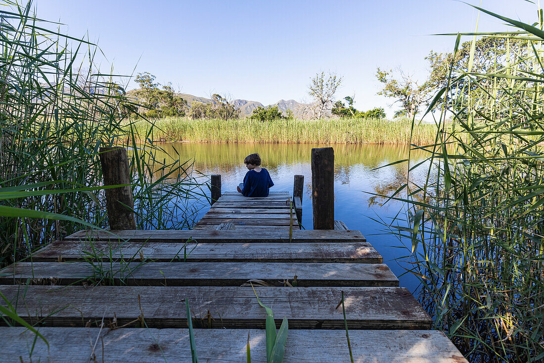 South Africa, Stanford, Boy (8-9) sitting on wooden pier
