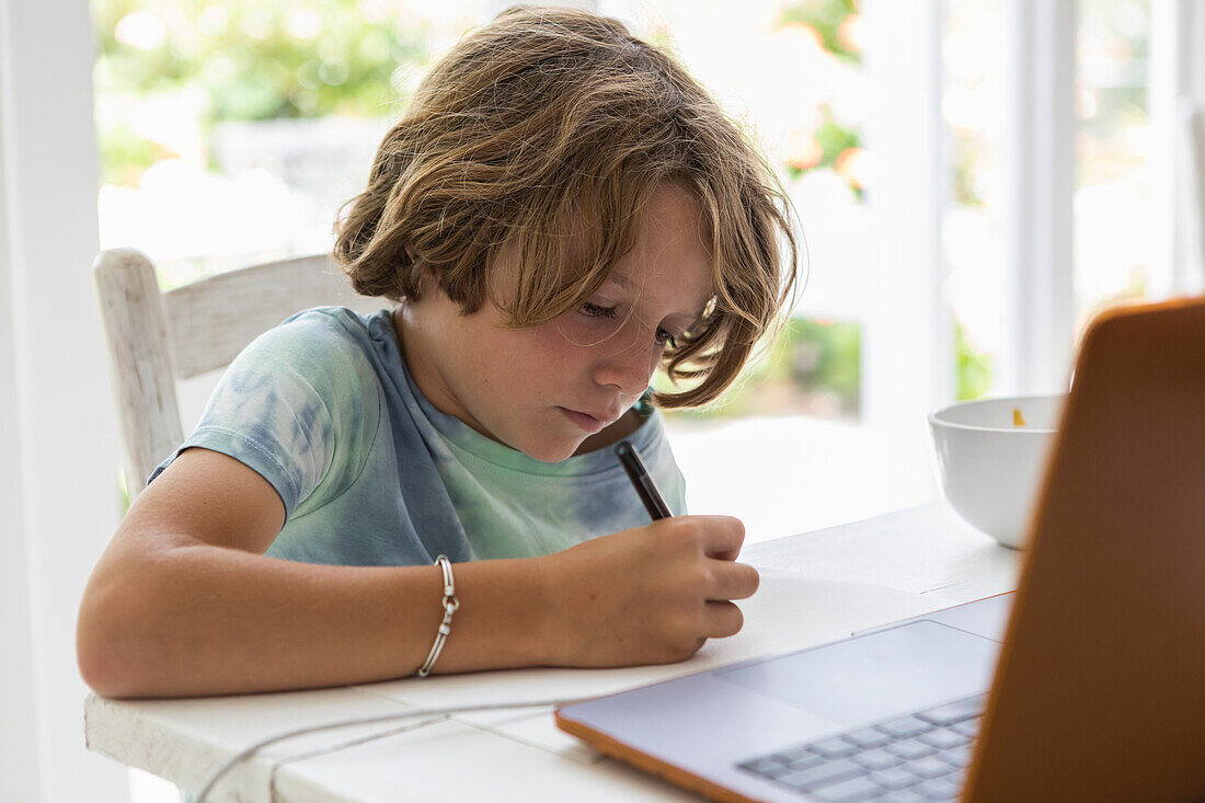 Junge (8-9), der während des Online-Unterrichts ein Bild zeichnet