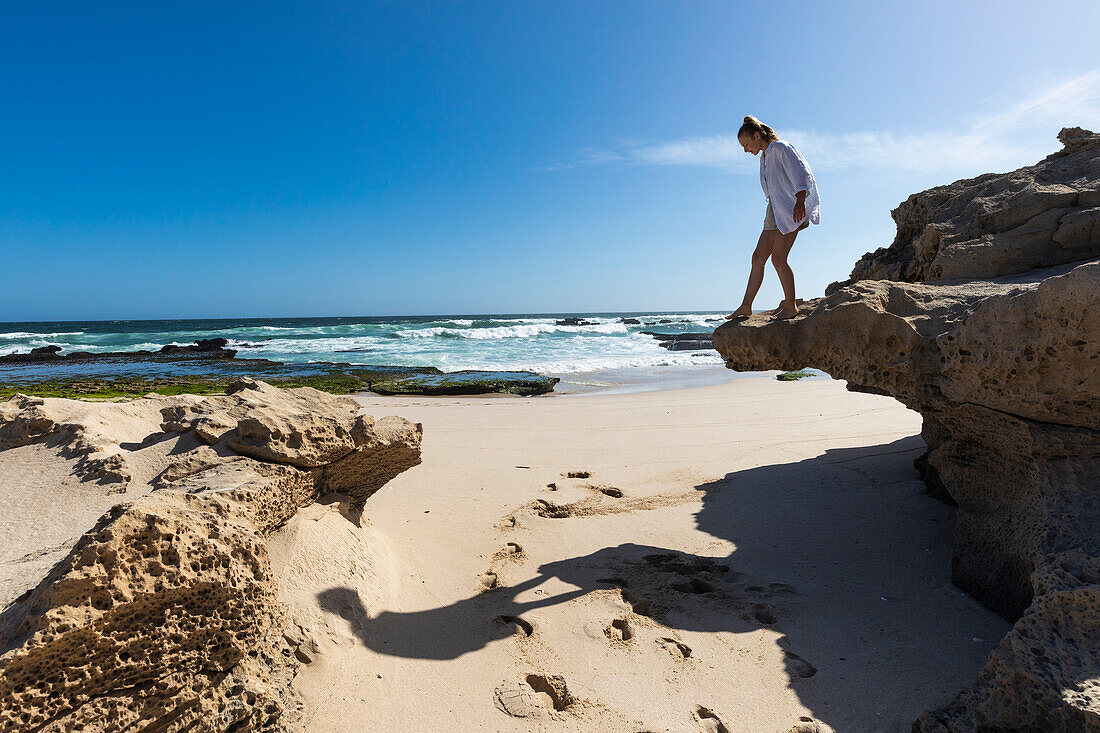 Südafrika, Westkap, Mädchen (16-17) balanciert auf einem Felsen am Strand im Lekkerwater-Naturreservat