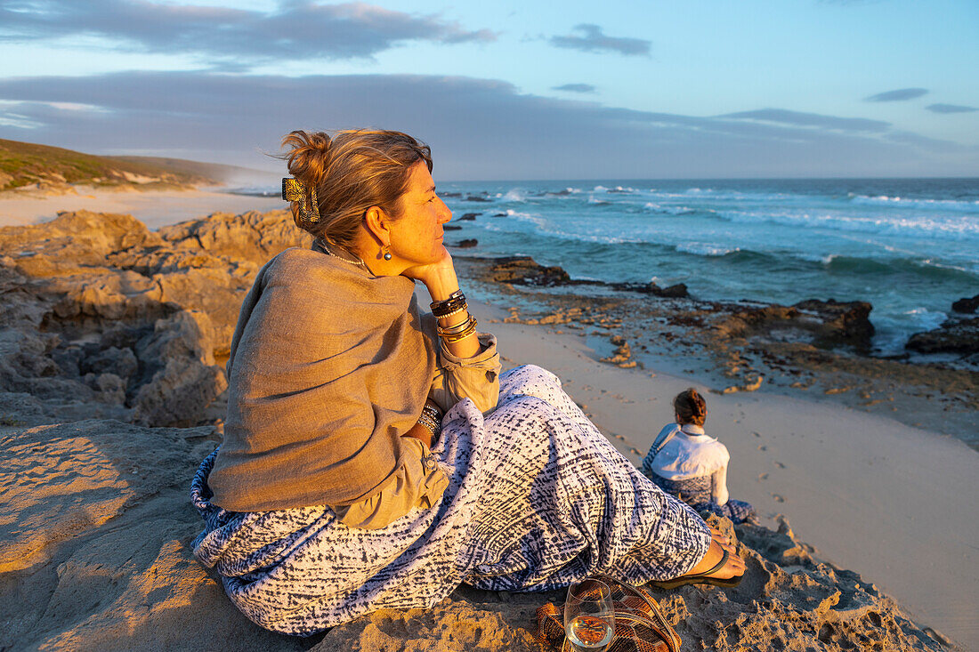 South Africa, Western Cape, Woman sitting on beach looking at ocean in Lekkerwater Nature Reserve