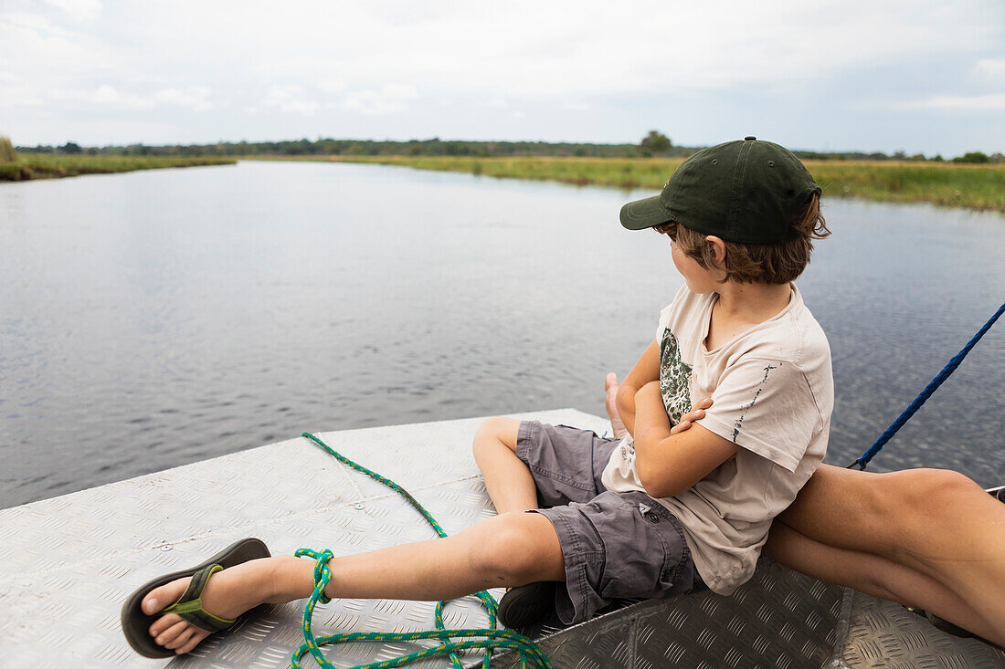 Africa, Zambia, Boy (8-9) in boat on Zambezi River near Tongabezi River Lodge