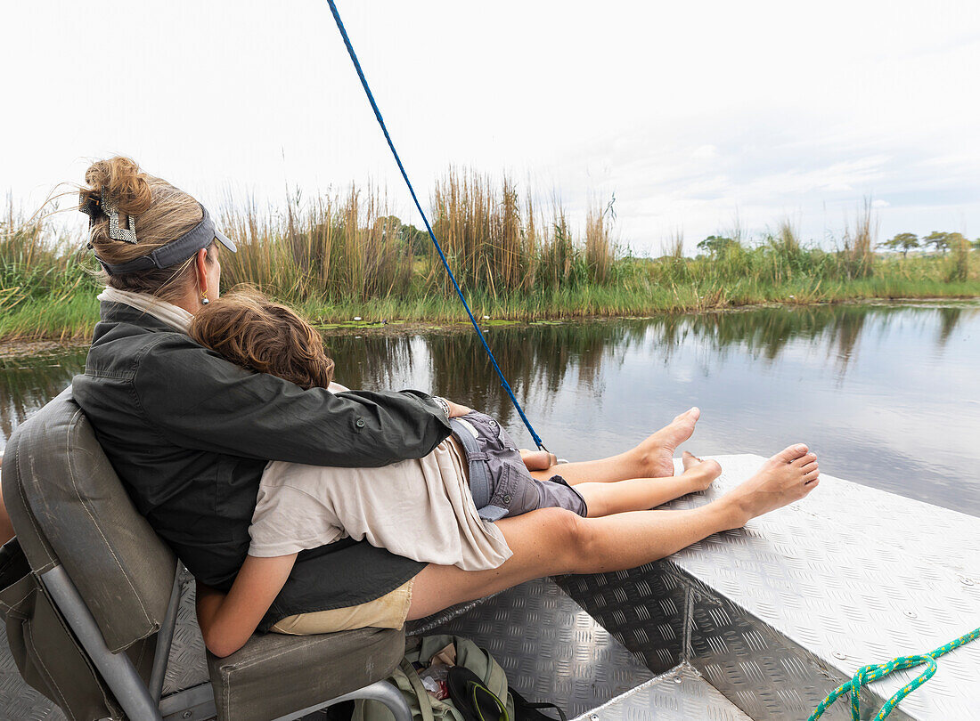 Africa, Zambia, Mother and son (8-9) in boat on Zambezi River near Tongabezi River Lodge