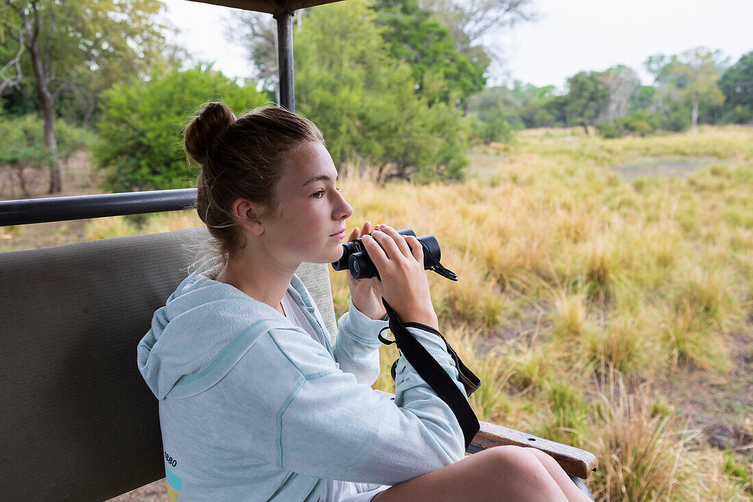 Africa, Zambia, Livingstone, Girl (16-17) in safari vehicle using binoculars