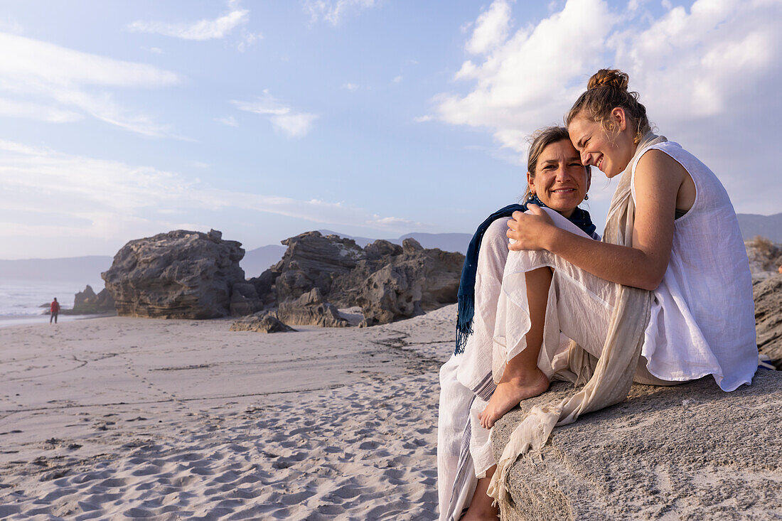 South Africa, Hermanus, Mother and daughter (16-17) relaxing on beach