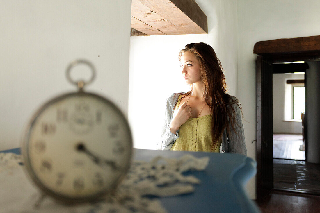 Junge Frau in altem Cottage, Uhr im Vordergrund