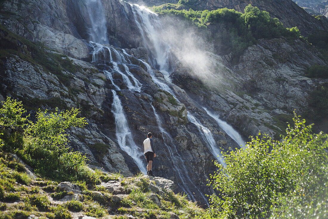 Russland, Karatschai-Tscherkessien, Arkhyz, Mann in der Nähe des Sofiyskiye Vodopady-Wasserfalls im Kaukasusgebirge