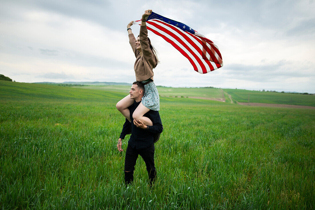 Young couple with American flag in wheat field