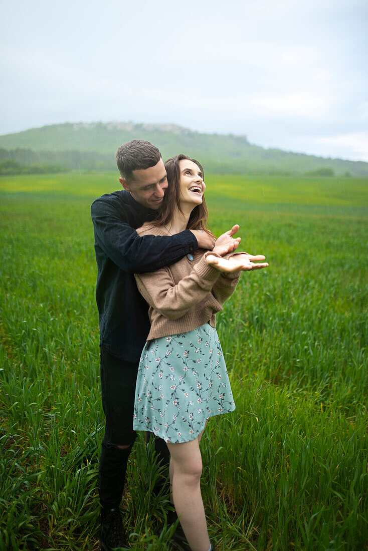 Young couple embracing in wheat field in rain