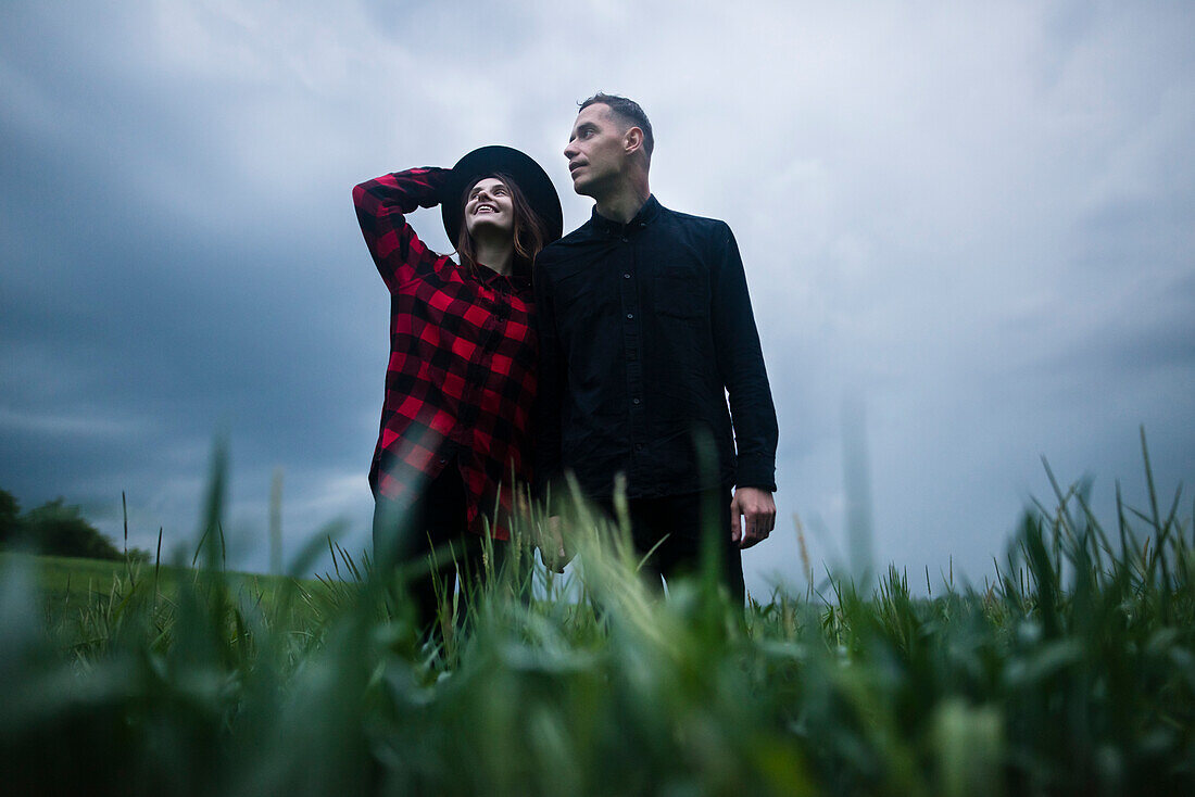 Young couple wrapped in wheat field on overcast day