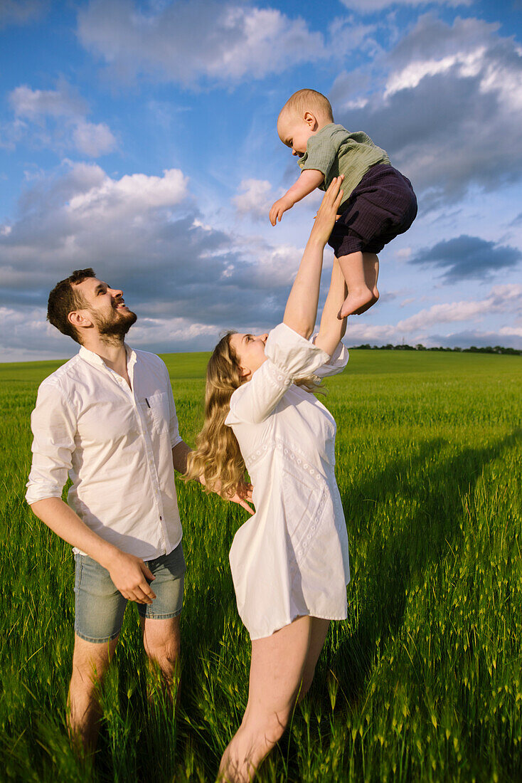 Parents playing with baby son (12-17 months) in agricultural field