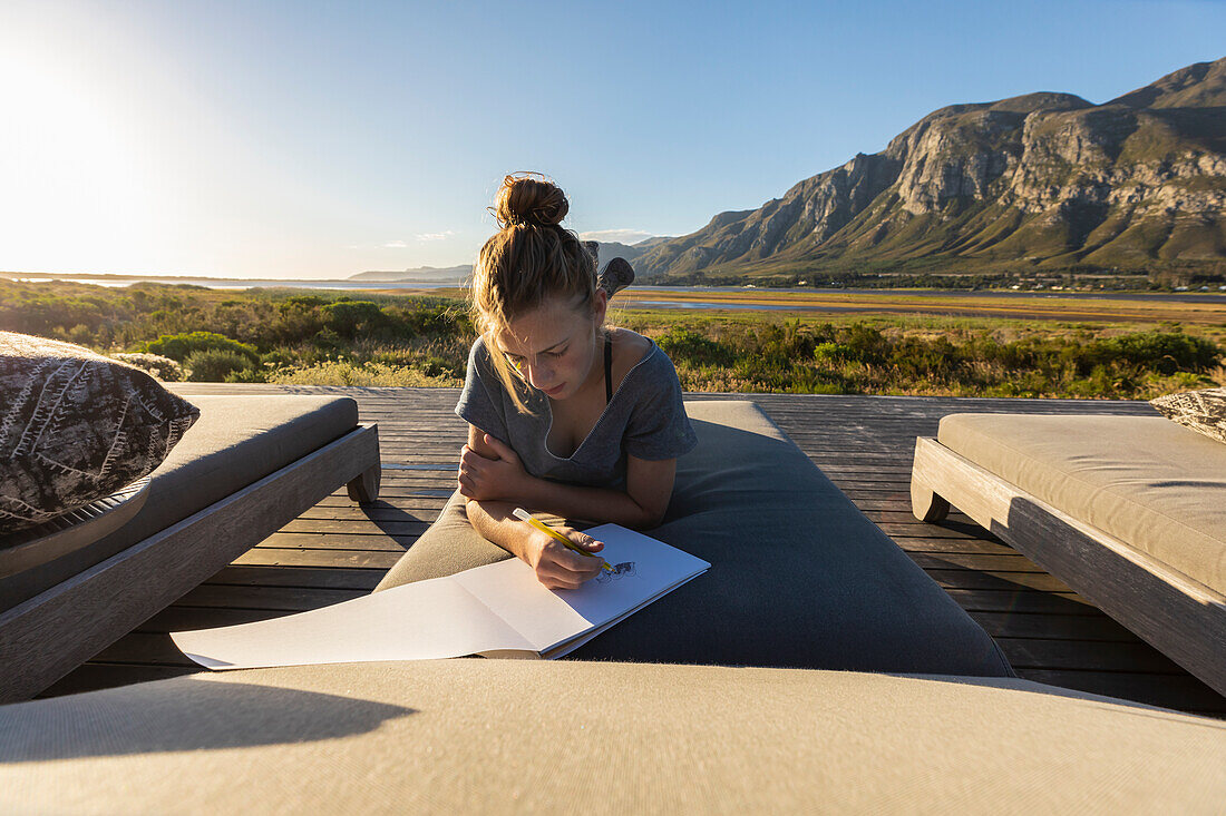 Südafrika, Stanford, Mädchen (16-17) entspannt sich auf der Terrasse und zeichnet im Skizzenblock