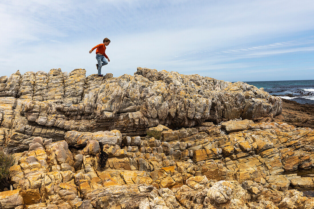 Südafrika, Hermanus, Junge (8-9) erkundet die Felsen am Sandbaai Beach