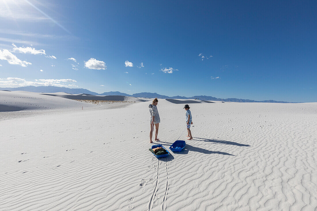 Vereinigte Staaten, New Mexico, White Sands National Park, Bruder (10-11) und Schwester mit Schlitten in der Wüste