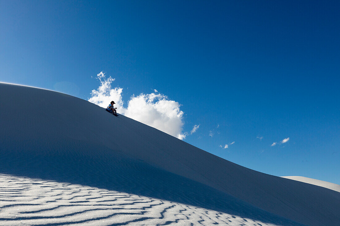 Vereinigte Staaten, New Mexico, White Sands National Park, Junge (10-11) beim Sandboarding in der Wüste