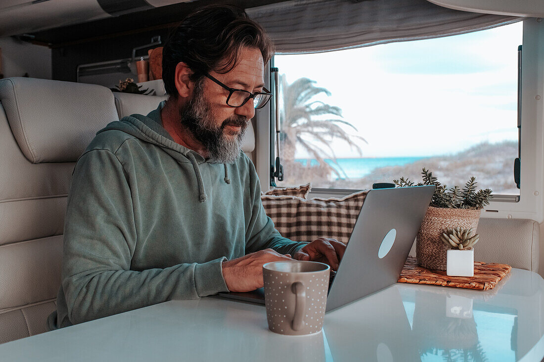 Man sitting in mobile home and working on laptop