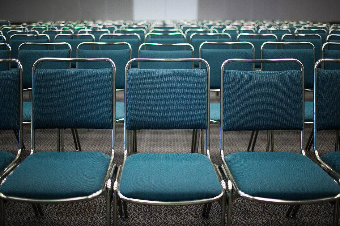 Reihen von leeren blauen Stühlen im Konferenzraum