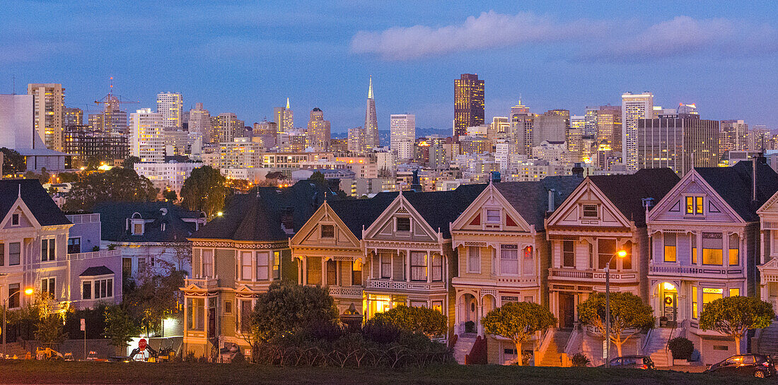 San Francisco, California, Painted Ladies, Victorian homes and city in background at Alamo Square at Hayes Street and Steiner Street at sunset