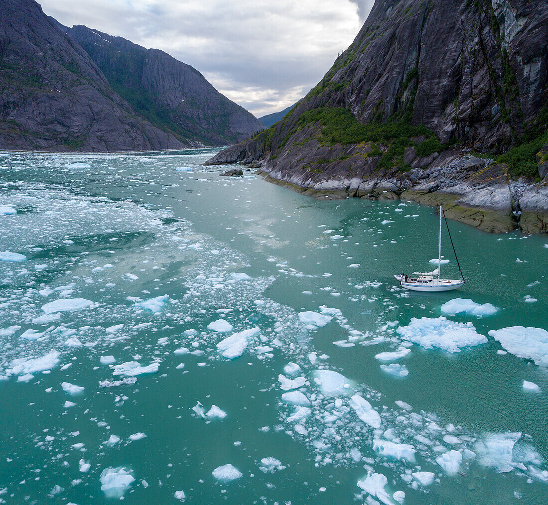 USA, Alaska, Luftaufnahme der S/V Abuelos, die an einem Sommerabend zwischen Eisbergen nahe der kalbenden Wand des LeConte-Gletschers östlich von Petersburg treibt