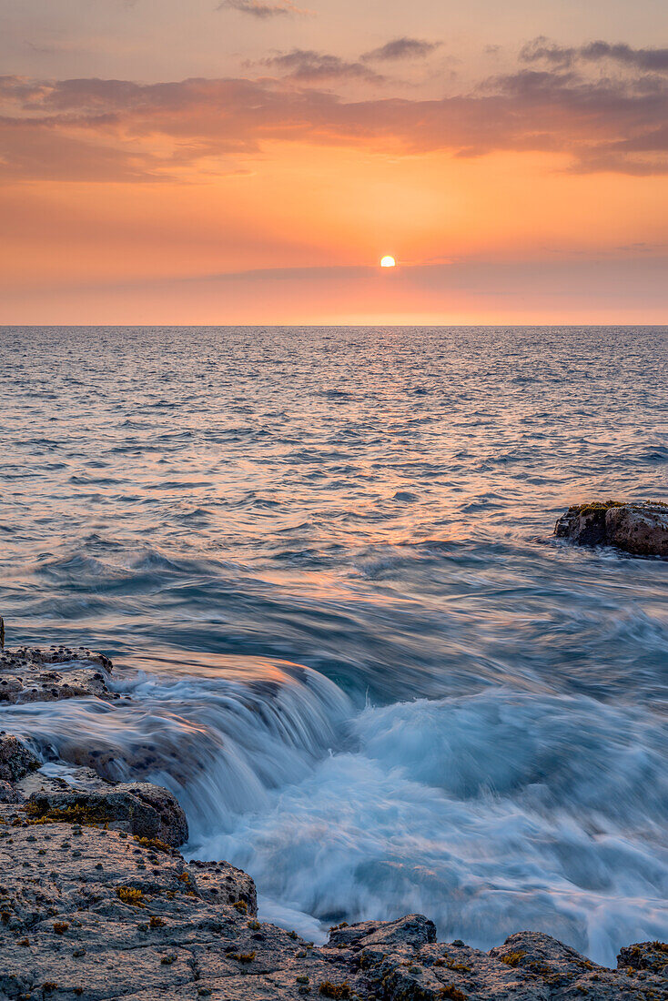 USA, Hawaii, Big Island von Hawaii. Wawaloli Beach Park, Der Sonnenuntergang hebt die Wellen und die felsige Küste hervor.