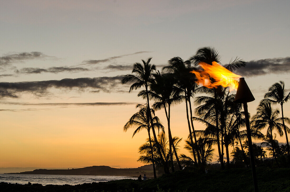 Tiki-Fackeln bei Sonnenuntergang am Strand von Poipu auf Kauai, Hawaii.