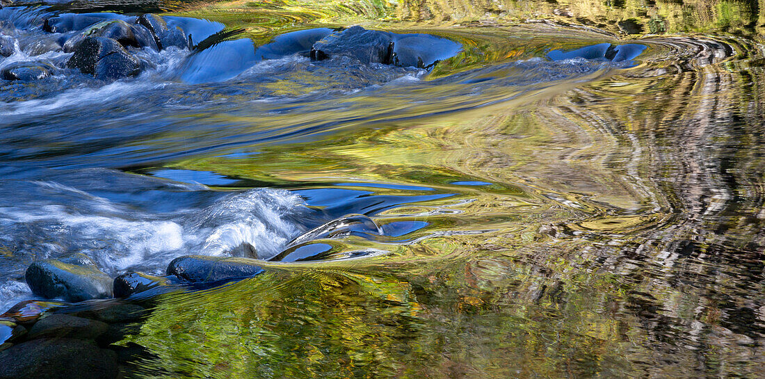 USA, Oregon. Abstrakte Herbstfarben, die sich in den Stromschnellen des Wilson River spiegeln