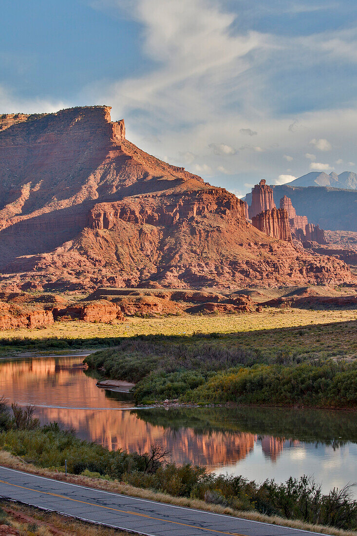 Fisher Towers spiegeln sich im Colorado River mit dem Highway darunter, Utah im Abendlicht