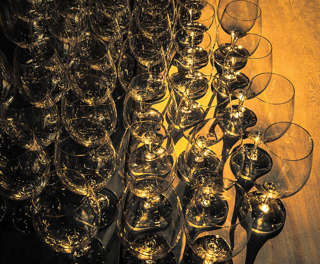 USA, Washington State, Walla Walla. Pattern of empty wine glasses in rich sunlight on wooden table.