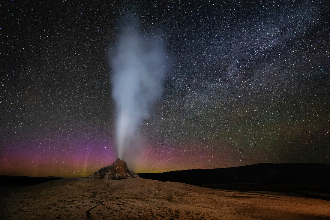 USA, Wyoming, Yellowstone National Park. Aurora and Milky Way above erupting White Dome Geyser