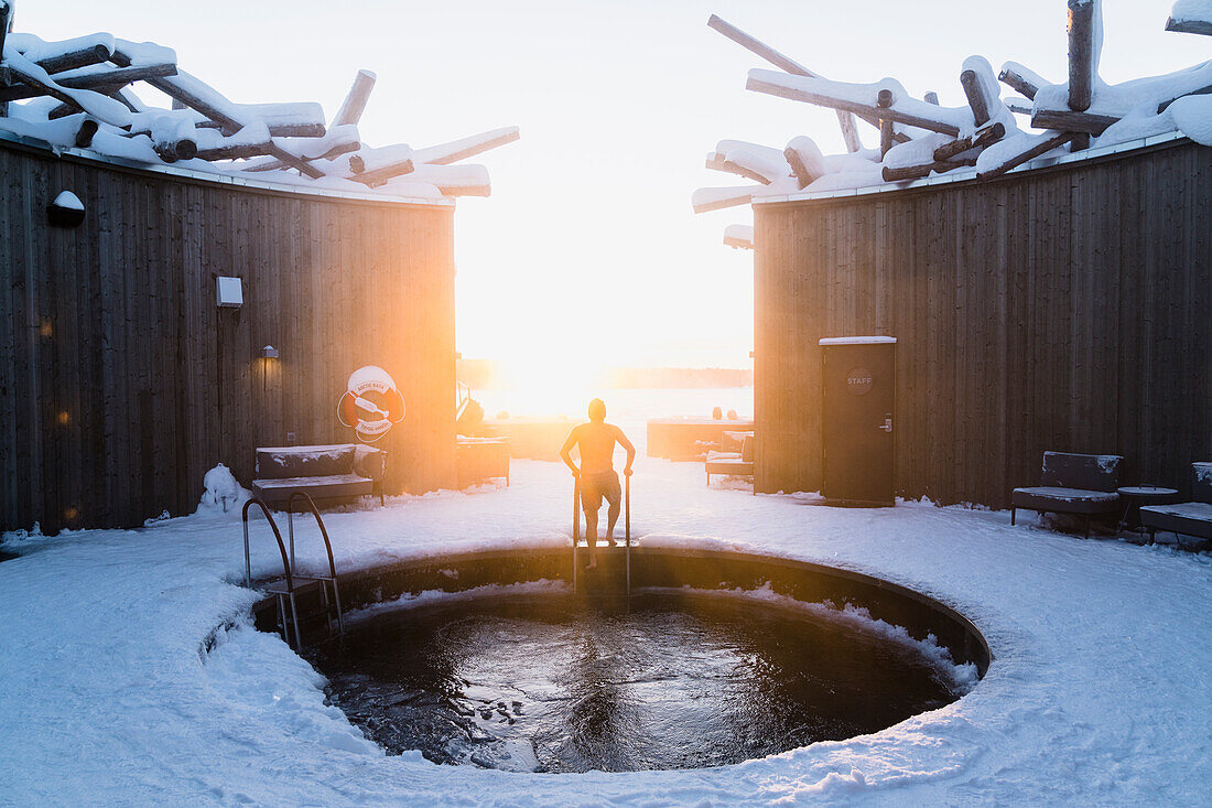 Eine Person genießt die kalten Bäder unter freiem Himmel im runden Pool des Arctic Bath Spa Hotels, Harads, Lappland, Schweden, Skandinavien, Europa
