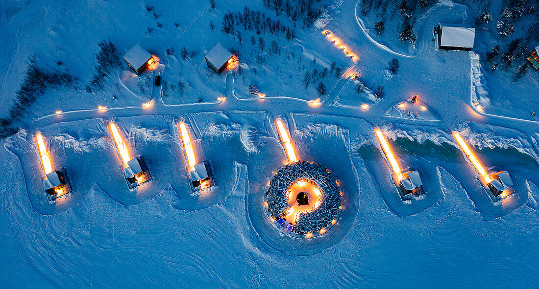 Die Kabinen des luxuriösen Arctic Bath Spa Hotels schwimmen in der Abenddämmerung auf einem zugefrorenen, schneebedeckten Fluss, Harads, Lappland, Schweden, Skandinavien, Europa
