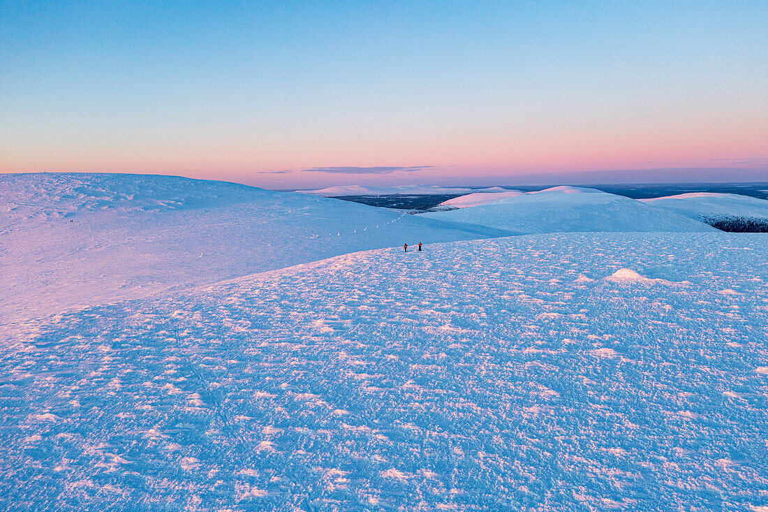 Luftaufnahme von Wanderern beim Skilanglauf bei Sonnenuntergang, Pallas-Yllastunturi-Nationalpark, Muonio, Lappland, Finnland, Europa